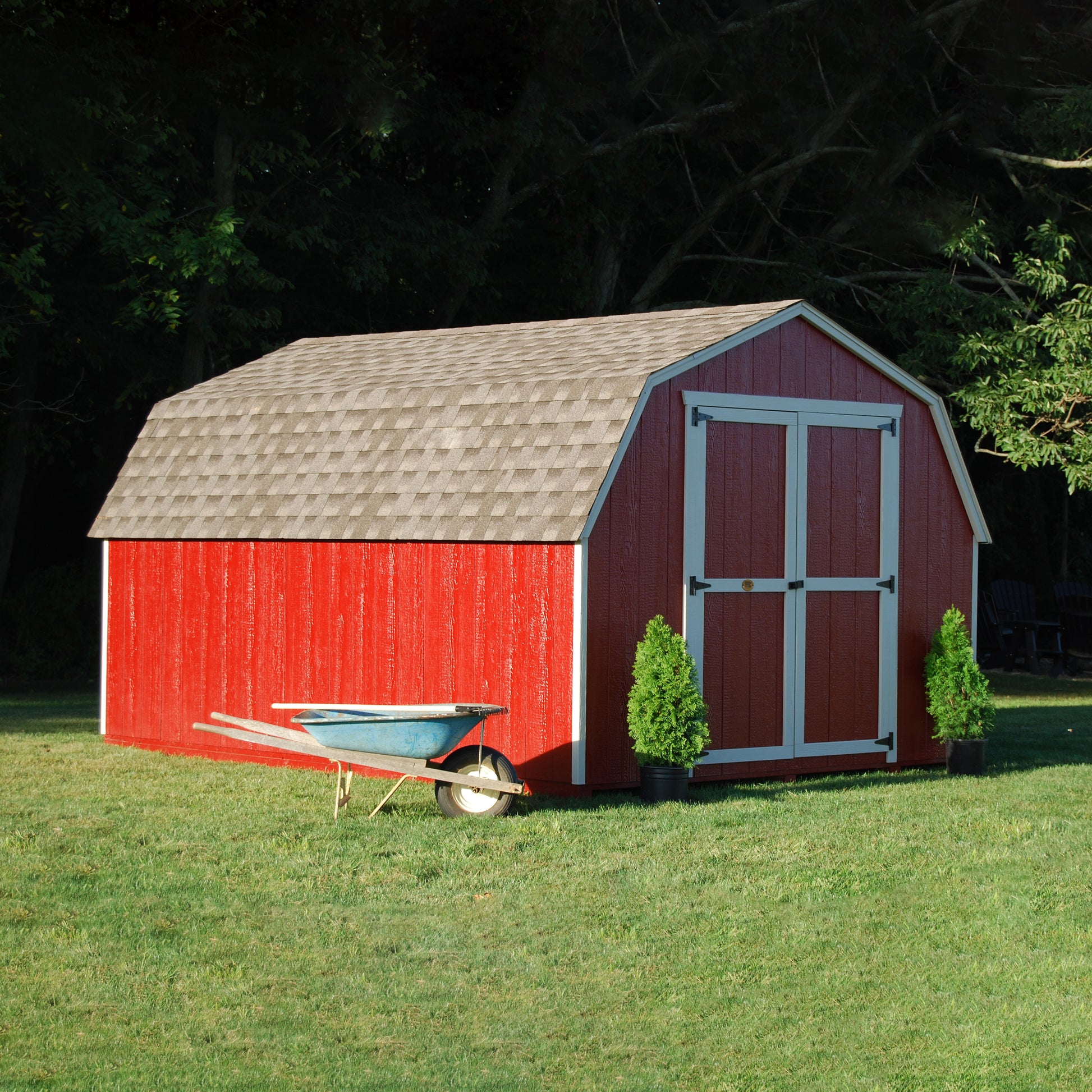 value gambrel barn with 4 foot sidewalls lifestyle picture with wheelbarrow beside it